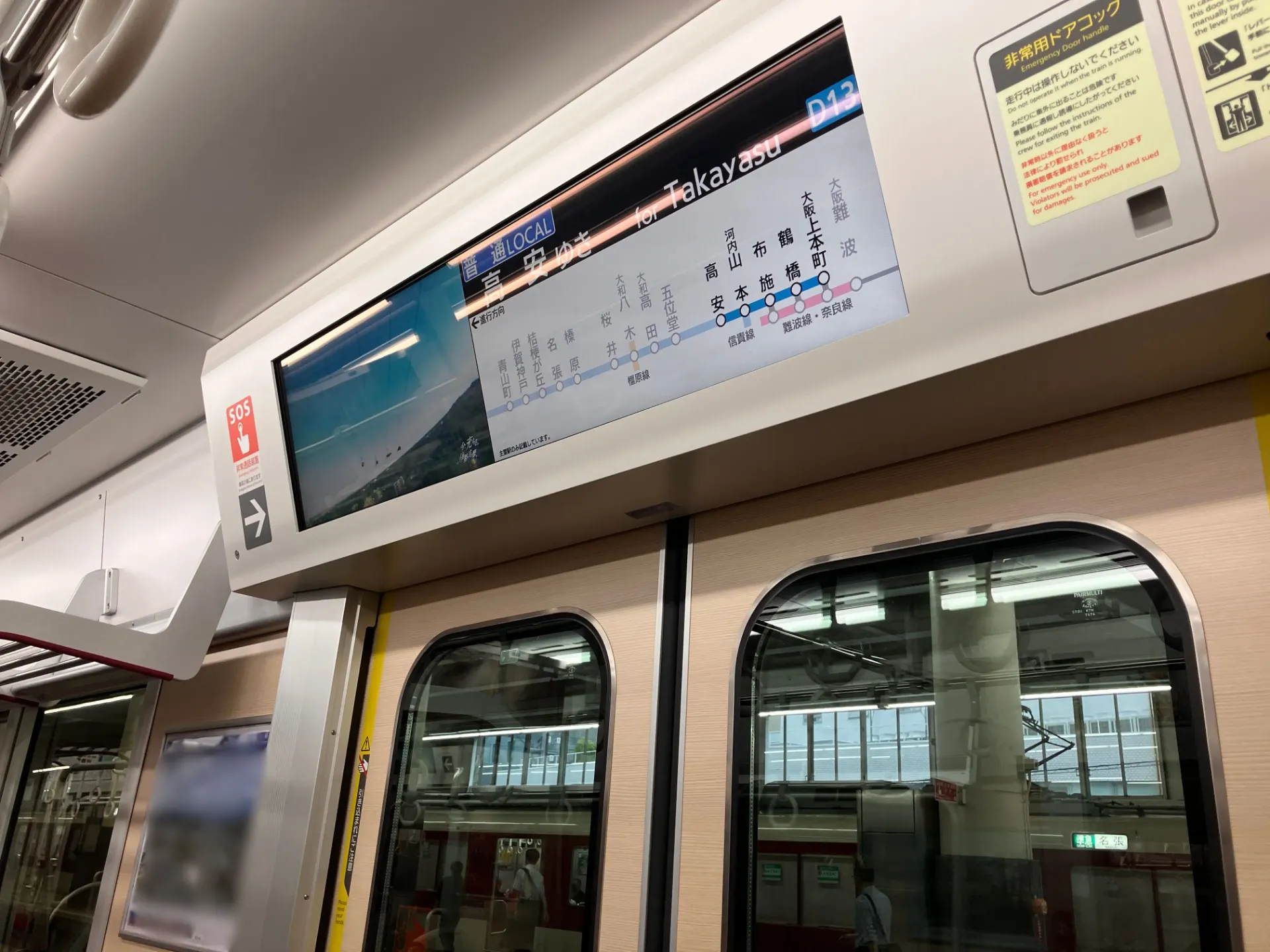 電車ドア上部に設置された液晶ディスプレイ(車内ビジョン)デジタルサイネージ。路線図と動画広告の二面表示。