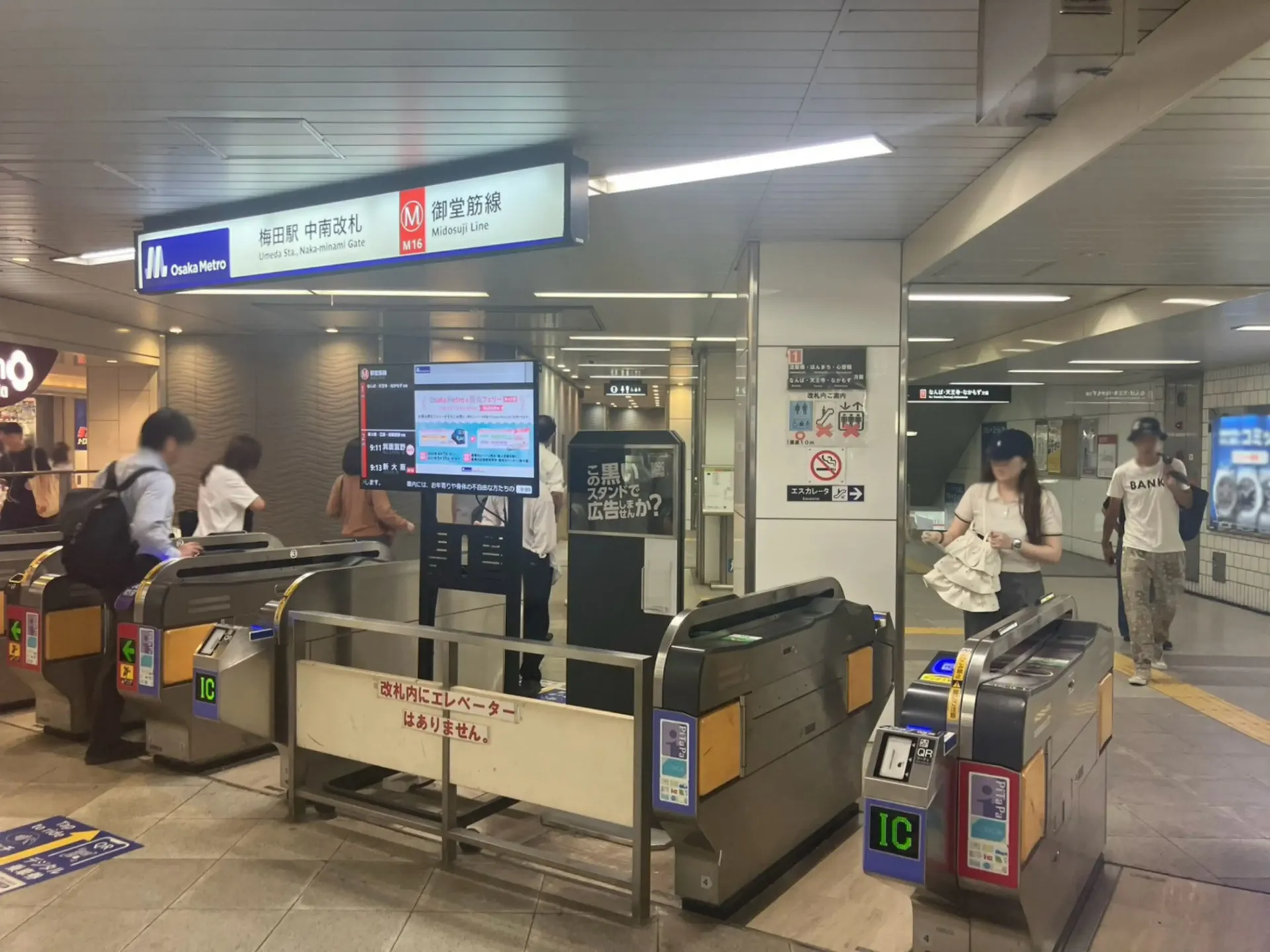 大阪メトロ御堂筋線梅田駅の中南改札付近における時刻表ラッピング広告かいさつ君の裏面と設置ロケーション全景