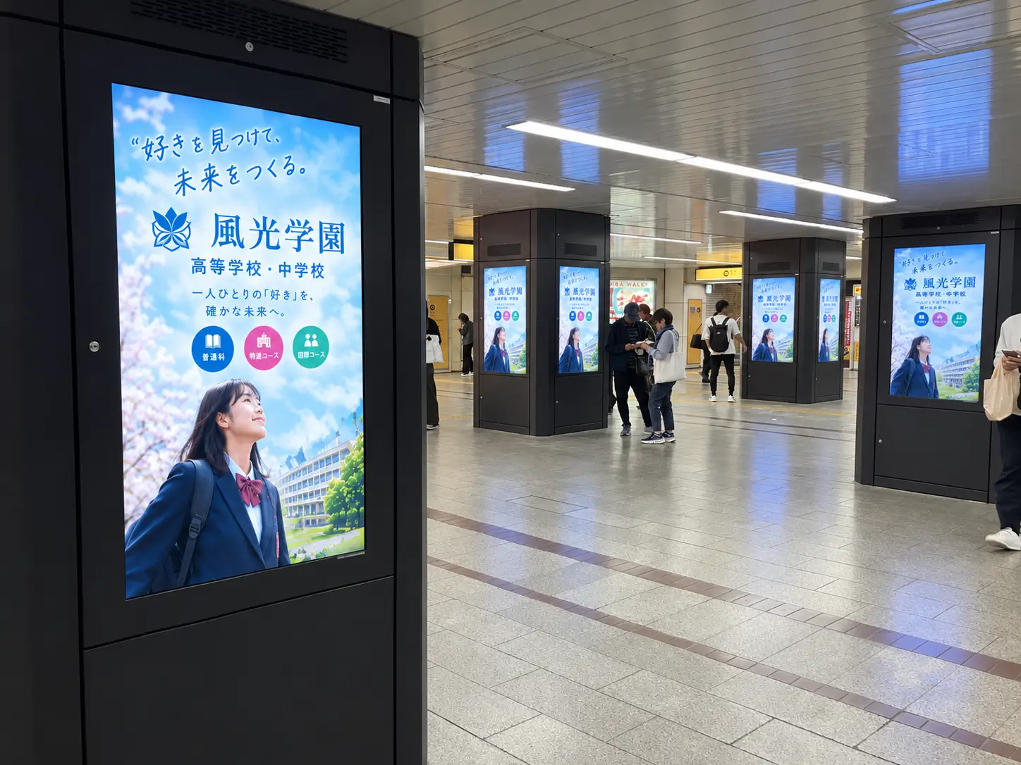なんば駅コンコースの柱に並ぶデジタルサイネージ「ネットワークビジョンなんば」に映し出された学校案内広告
